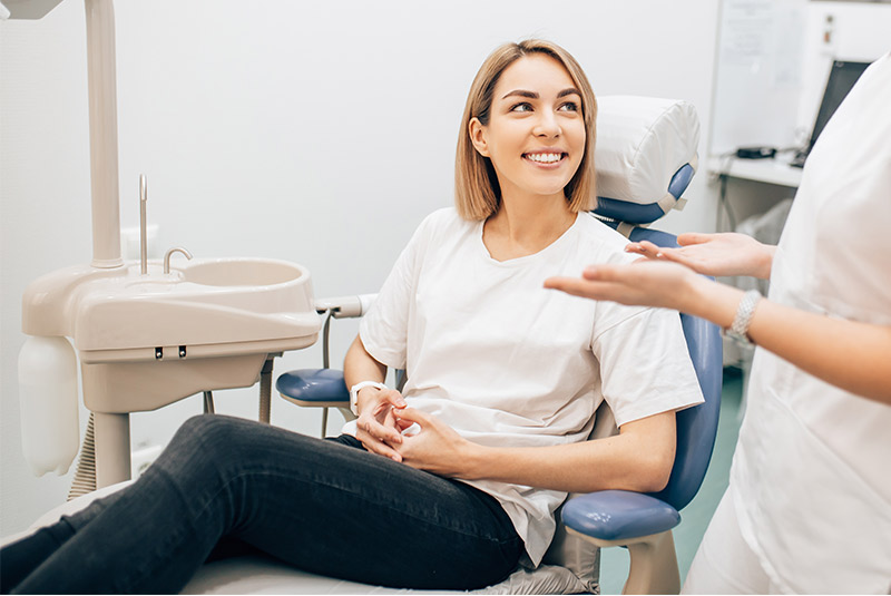Very nice lady with dirty blonde hair smiling in dental chair looking at doctor